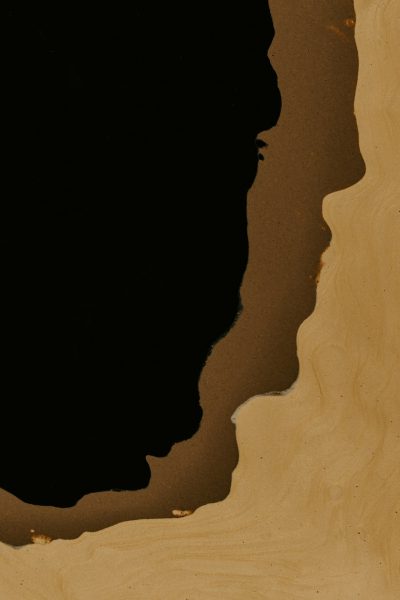 Extreme close up of an edge silhouette on the left side of beige wood grain with a black background, only showing the shape of a person's head and shoulders, ink drawing in the style of minimalist, flat illustration, warm tones, low contrast. --ar 85:128