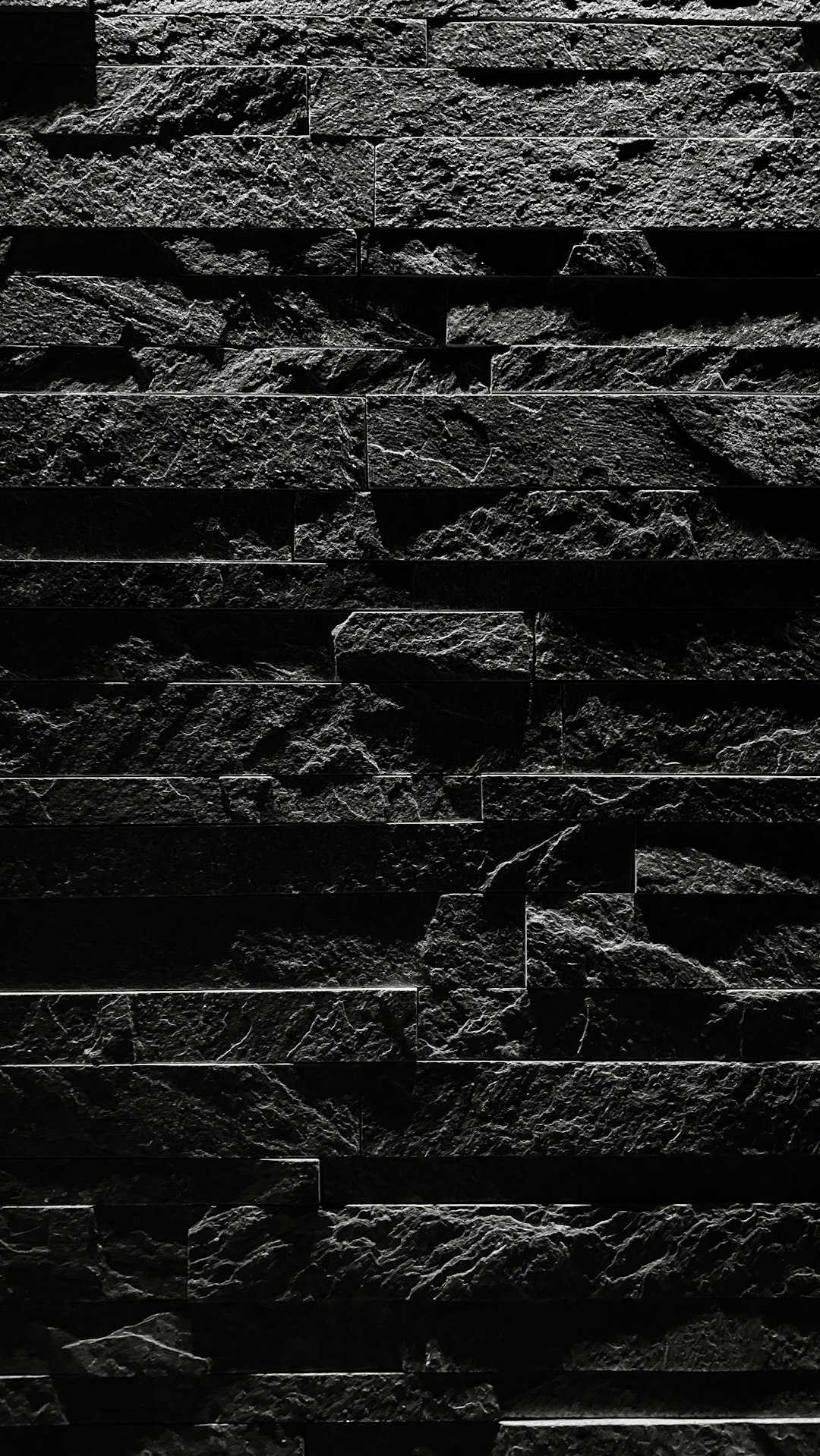 black stone wall, minimalistic, simple, dark background, black and white, high contrast, low angle shot, straight on, front view, texture, depth of field, ultra realistic, cinematic lighting, high resolution photography –ar 9:16