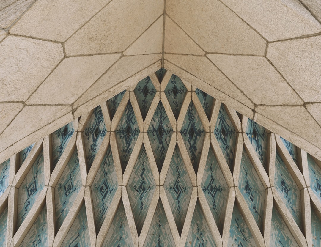 A closeup shot of the architecture detail, showcasing intricate geometric patterns on stone and ceramic tiles in pastel blue hues. The perspective is from an elevated angle, capturing the symmetrical arrangement of these elements that form delicate diamond shapes with perfect symmetry across the arches. This detailed photograph highlights the beauty and complexity found within architectural design. Shot in the style of Alex CTYRINAS using a Sony Alpha A7 III camera with a FE24mm F/5 G lens at an f/8 aperture setting, at ultra high definition. –ar 64:49