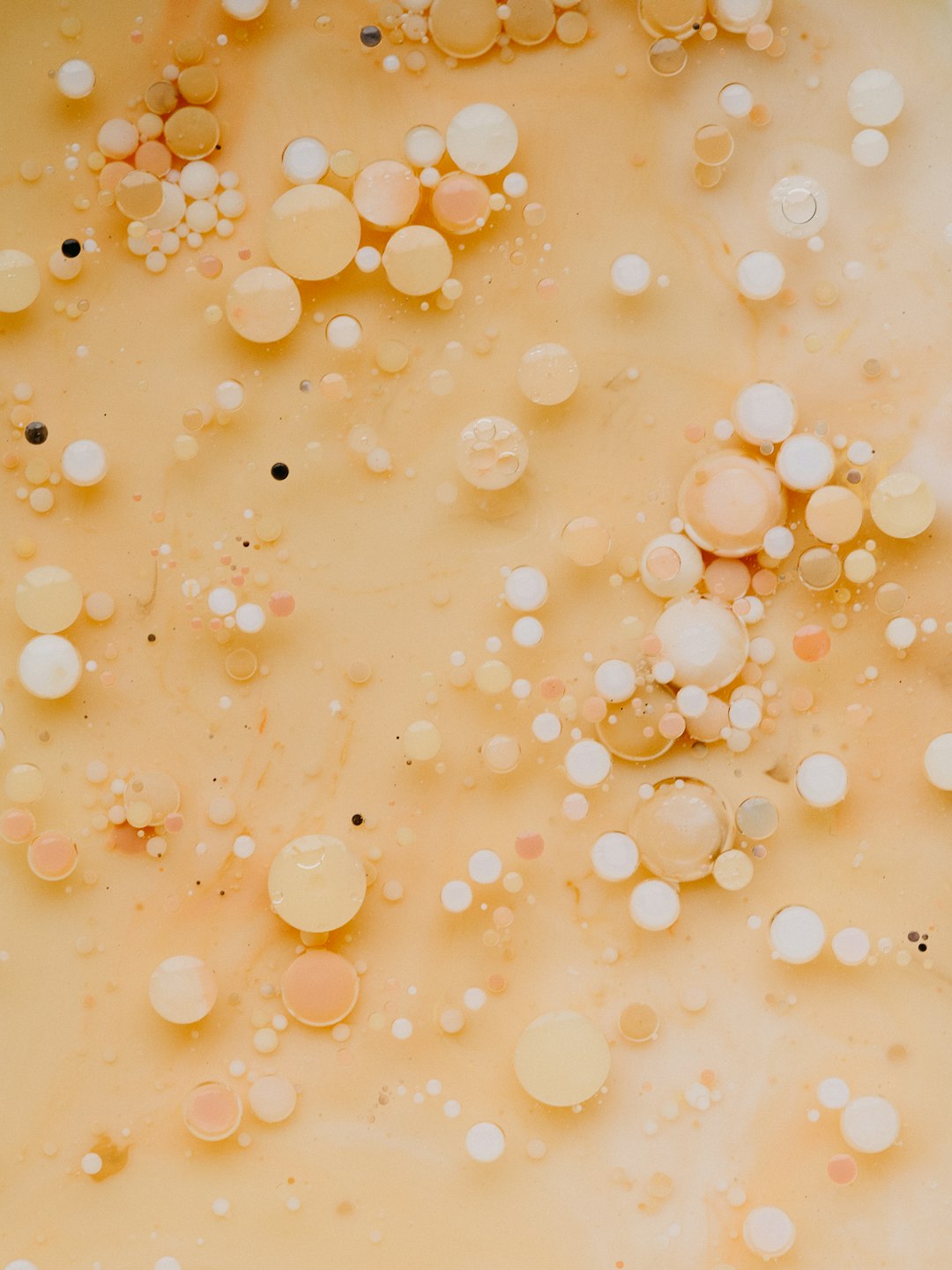 An editorial minimalistic photo of an abstract with many tiny white, black and pastel peach colored bubbles floating in the air on top of beige milk, close up shot. The composition is symmetrical with an empty background, in the style of [Rineke Dijkstra](https://goo.gl/search?artist%20Rineke%20Dijkstra). –ar 3:4