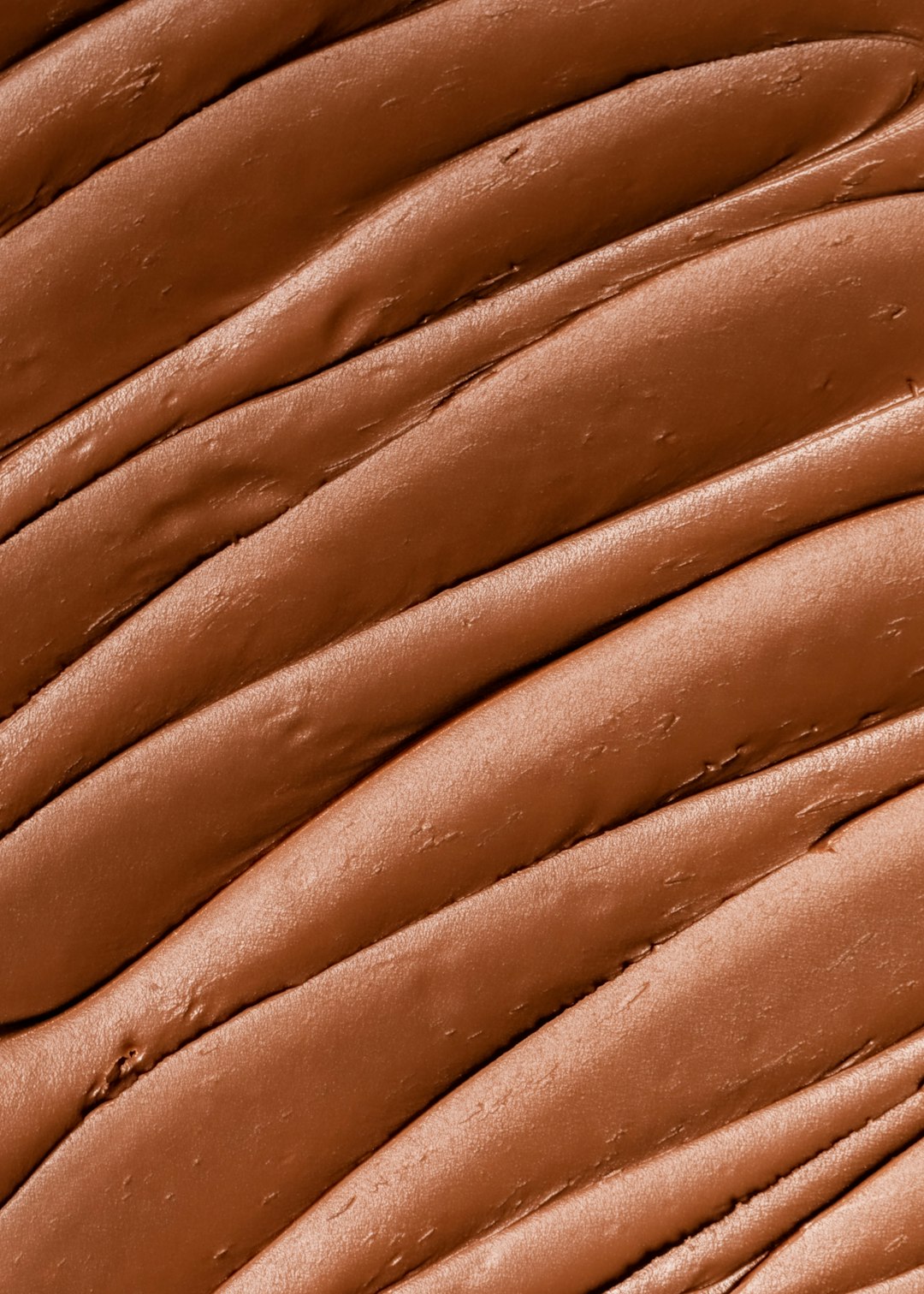 A closeup of the texture and color of liquid foundation in a chocolate brown color. The skin is slightly wavy with natural patterns, creating an elegant appearance. A macro shot focuses on one area to highlight details such as fine lines or delicate textures. This image should convey luxury and beauty through its detailed depiction of smooth skin in the style of elegant appearance. –ar 91:128