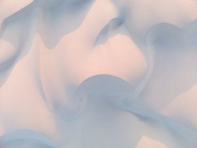 close up shot of an abstract pastel white background with a few light blue shapes, almost completely covered by soft light pink and dark beige gradient in the shape of waves --ar 4:3