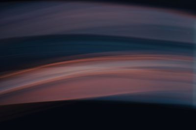 A blurred photograph of an abstract background with soft lines and curves in the style of lightbox, with dark navy blue and pink colors. The picture shows a dark landscape with an atmospheric sky, bathed in a warm glow. It uses long exposure photography techniques to create a dark atmosphere with a gradient of colors. The low angle shot has a horizontal line composition, centered in the frame with sharp focus and blurred edges. --ar 128:85