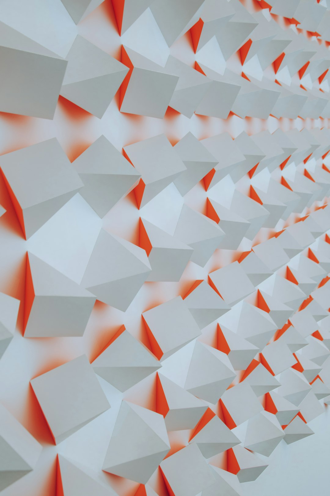 A wall of white and orange paper triangles, shown in close up, features geometric shapes arranged symmetrically in an art installation. The geometric shapes are arranged in the style of symmetrical art. –ar 85:128