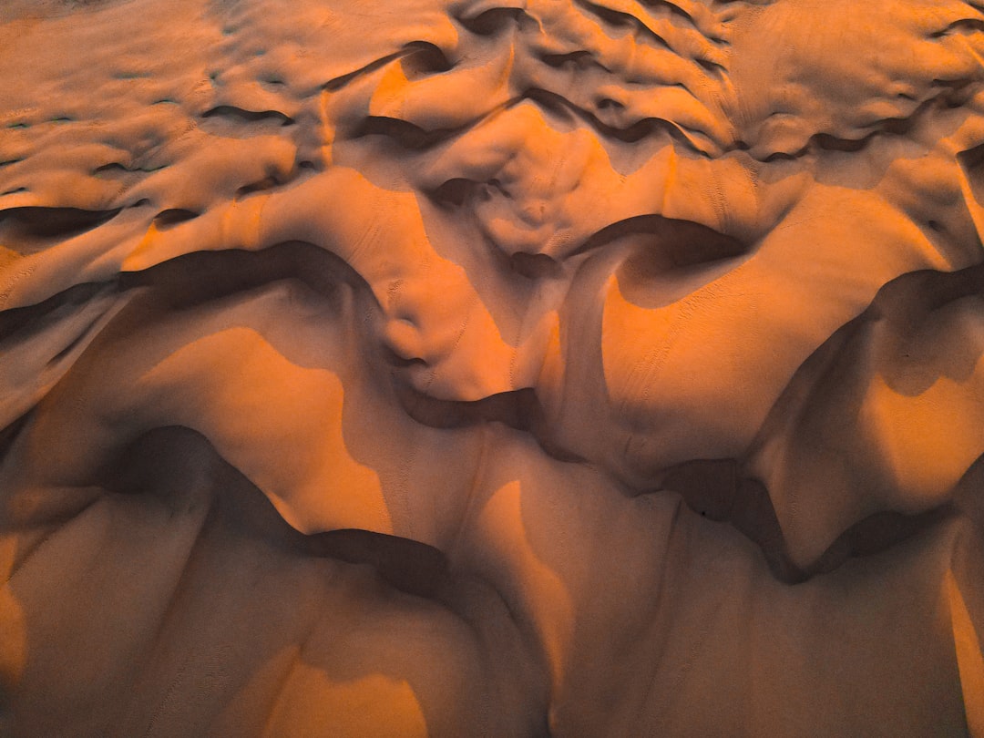 Dune pattern, top view of the desert at sunset, dunes with orange and brown colors, aerial photography, texture background, high resolution, high detail, hyper realistic, sharp focus, extreme long shot, natural light, beautiful, cinematic –ar 4:3