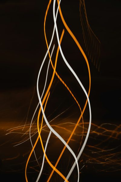 White and orange light trails on a black background, from a long exposure photograph, with vertical lines in dark yellow and white, streaks of lights forming glowing curves, from a long exposure. --ar 85:128