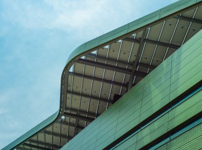 Modern architecture, green building facade with solar panels on the roof, curved eaves, sky background, closeup of details and texture, architectural photography, wideangle lens, sunlight exposure, perspective effect, modern style, urban landscape. --ar 128:95