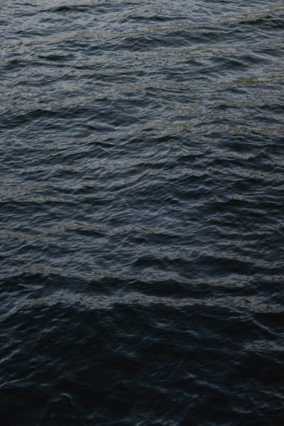 A dark gray sea with slight ripples on the water surface and no visible land in sight, presented in a clean and simple top view style reminiscent of hyperrealistic photography at a high resolution. --ar 85:128