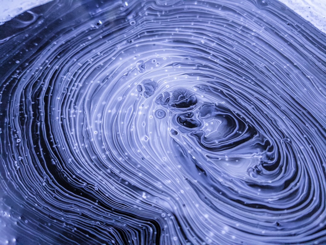 A close up of swirling liquid in the shape of electric field lines, monochromatic blue, dark grey and white, macro photography, low angle, overhead shot, Kodak film photo, in the style of kodak film. –ar 4:3