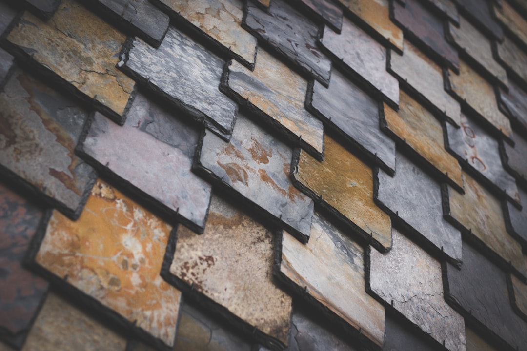 A close-up of the slate shingle wall, showcasing its unique texture and color palette. The pattern is intricate with different shades of gray, brown, and yellow, creating an artistic visual effect in the style of the wall. –ar 128:85