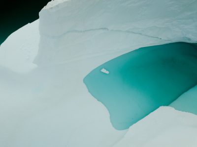 A view from above of an iceberg in the middle, with turquoise water inside, shot on Leica M6 using natural light and color film, in the style of high resolution. --ar 128:95