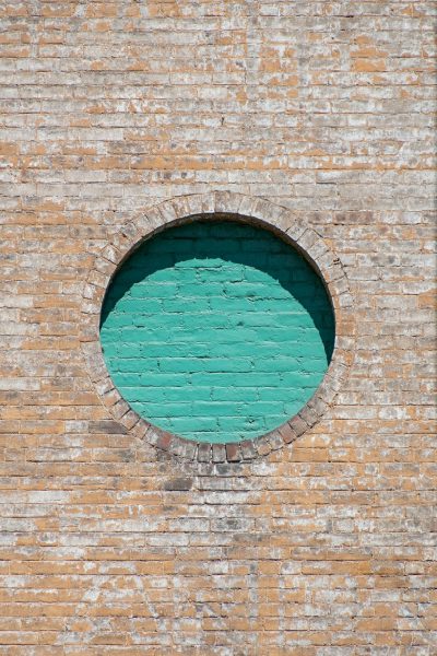 round window in brick wall, turquoise green paint on the outside of the window, architectural photography, New York city architecture. --ar 85:128