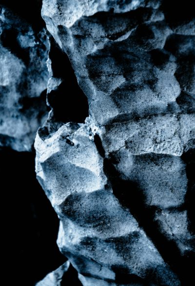 close up texture of rock, monochrome blue tones, dark background, low light, hyper realistic photography --ar 87:128