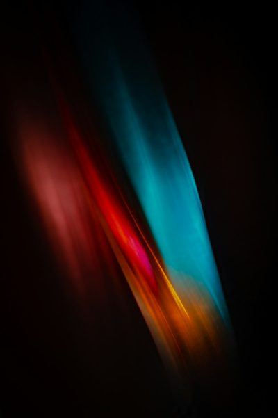 abstract blurred light streaks of color on black background, simple minimalistic color photography in the style of ron gonsalves and kellyAMI muted colors --ar 85:128