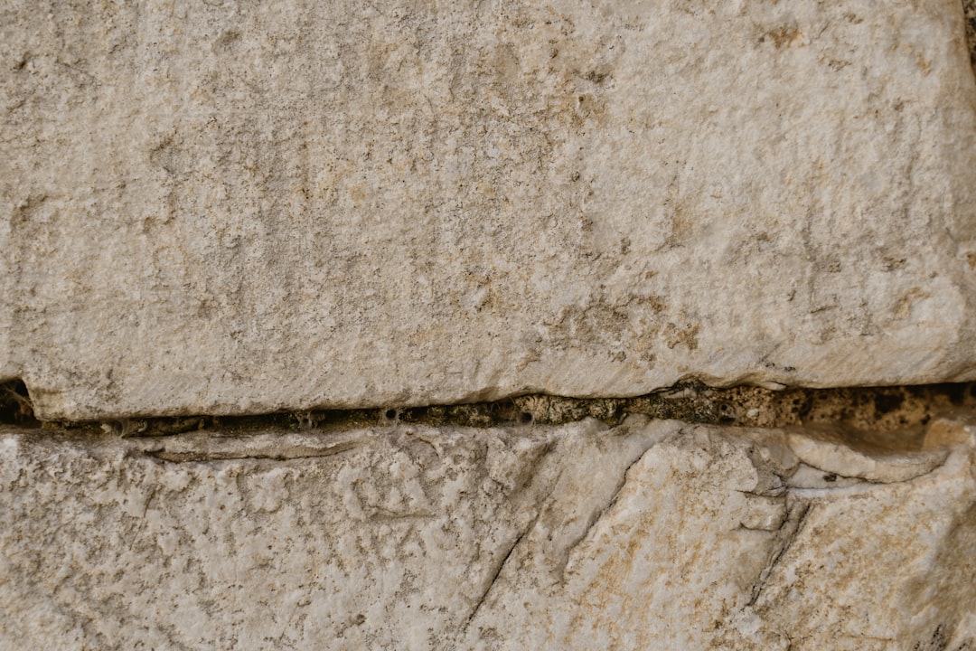 A closeup of the ancient Greek stone wall, showing signs of wear and tear with small cracks in its surface, highlighting textures that add depth to historical buildings. The photo was shot on a Sony Alpha A7R IV in the style of historical documentation. –ar 128:85