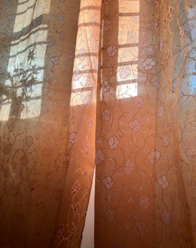 A close-up photo of an orange lace curtain with a floral pattern, sunlight through the window, pastel colors, in the style of [Wes Anderson](https://goo.gl/search?artist%20Wes%20Anderson). --ar 101:128