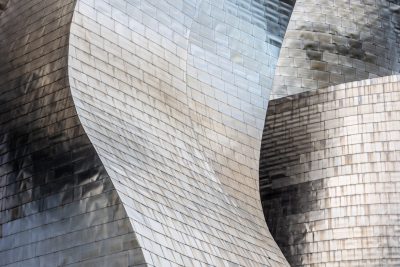 A closeup of the iconic Guggenheim building in the Basque style, made from shiny silver metal tiles, showcasing detailed textures and reflections on its surface. The focus is set at an angle to capture the unique architectural design. Shot with a Canon EOS R5 for sharpness and clarity. --ar 128:85