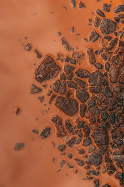 top view of brown and orange liquid with rocks floating in it, close up, macro photography, texture, top down perspective, hyper realistic, photo realism, high resolution, --ar 85:128