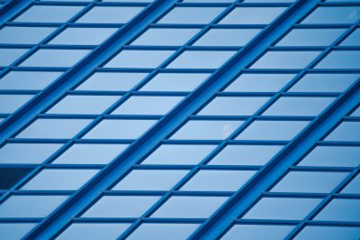 A blue glass building with diagonal grid lines in a minimalist style, closeup shot, high resolution photography, symmetrical composition, daylight, cool tone, focused on the geometric patterns of windows and steel frames. --ar 128:85