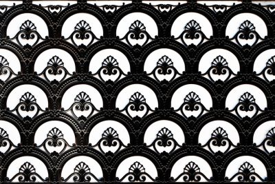 black and white symmetrical ornamental metalwork pattern, in the Victorian style with an art deco influence, featuring repeating geometric shapes like circles and arches in the design, all on a flat background --ar 128:85