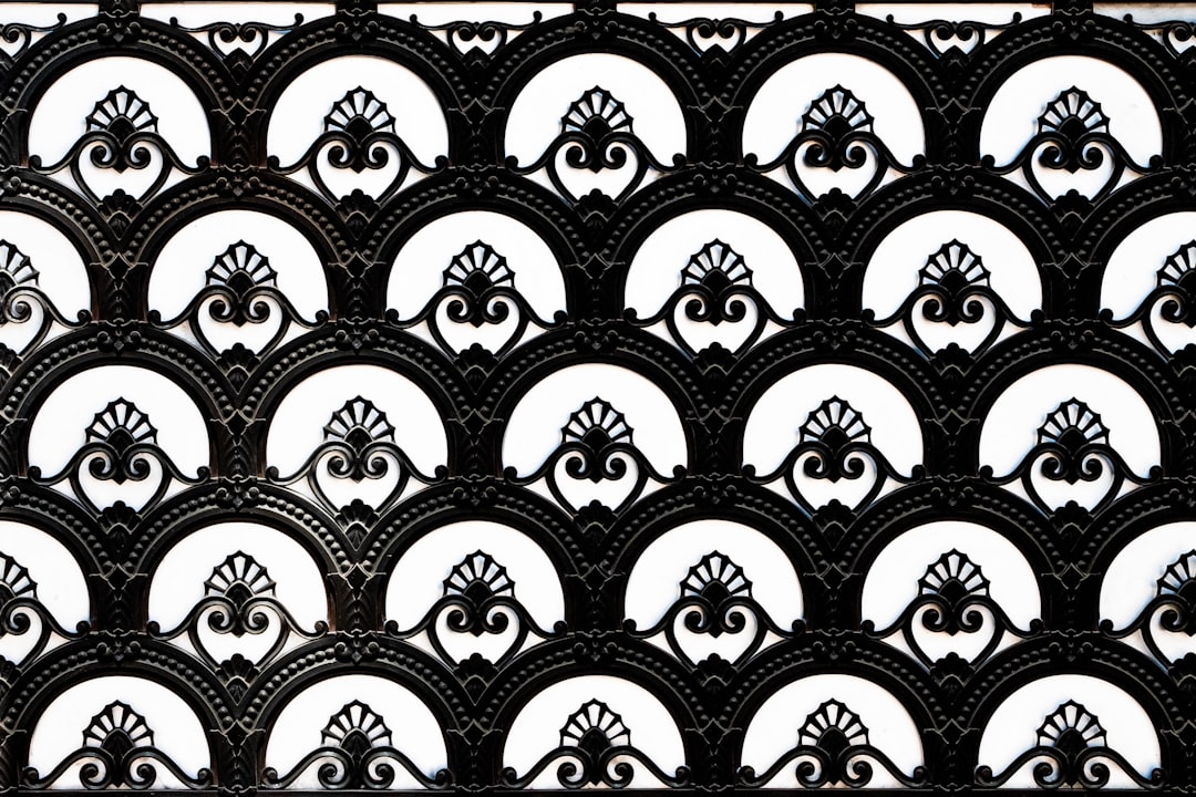 black and white symmetrical ornamental metalwork pattern, in the Victorian style with an art deco influence, featuring repeating geometric shapes like circles and arches in the design, all on a flat background –ar 128:85