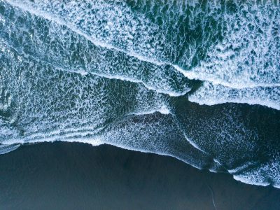 drone shot of ocean waves on a black sand beach, aerial view, drone photography, in the style of national geographic photo --ar 4:3