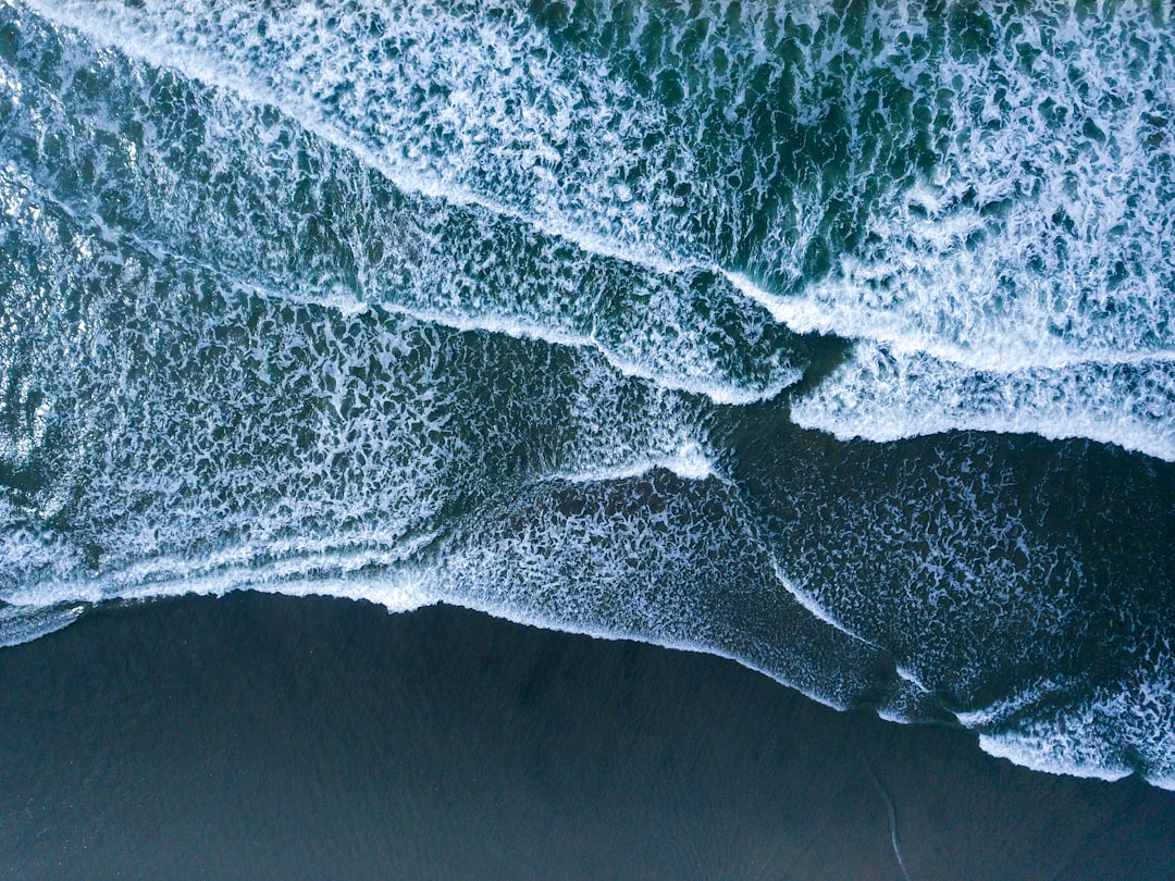 drone shot of ocean waves on a black sand beach, aerial view, drone photography, in the style of national geographic photo –ar 4:3