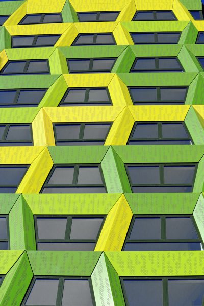 A green and yellow facade made of angular hexagons, a building in London with lots of windows, architectural photography in the style of different artists. --ar 85:128