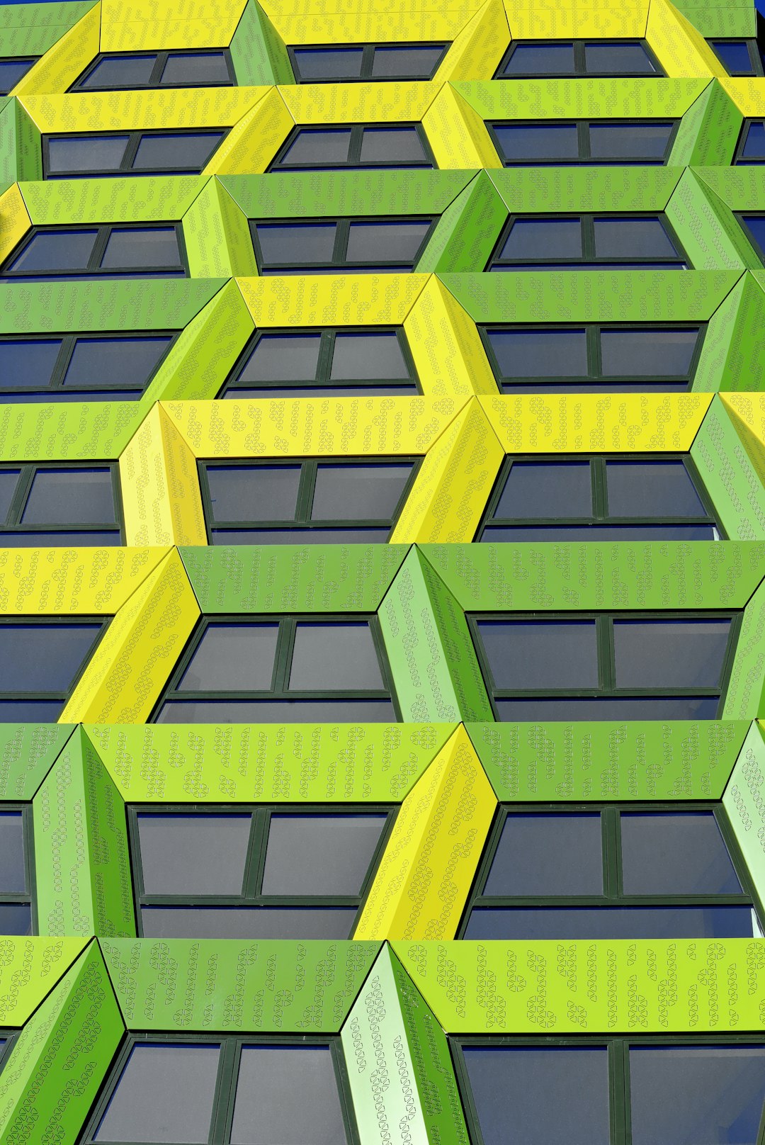 A green and yellow facade made of angular hexagons, a building in London with lots of windows, architectural photography in the style of different artists. –ar 85:128