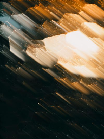 Abstract photo of ice floating in the dark, light rays through it, with light and shadow, gold leaf accents, closeup, blurred motion, dark background, cinematic --ar 3:4