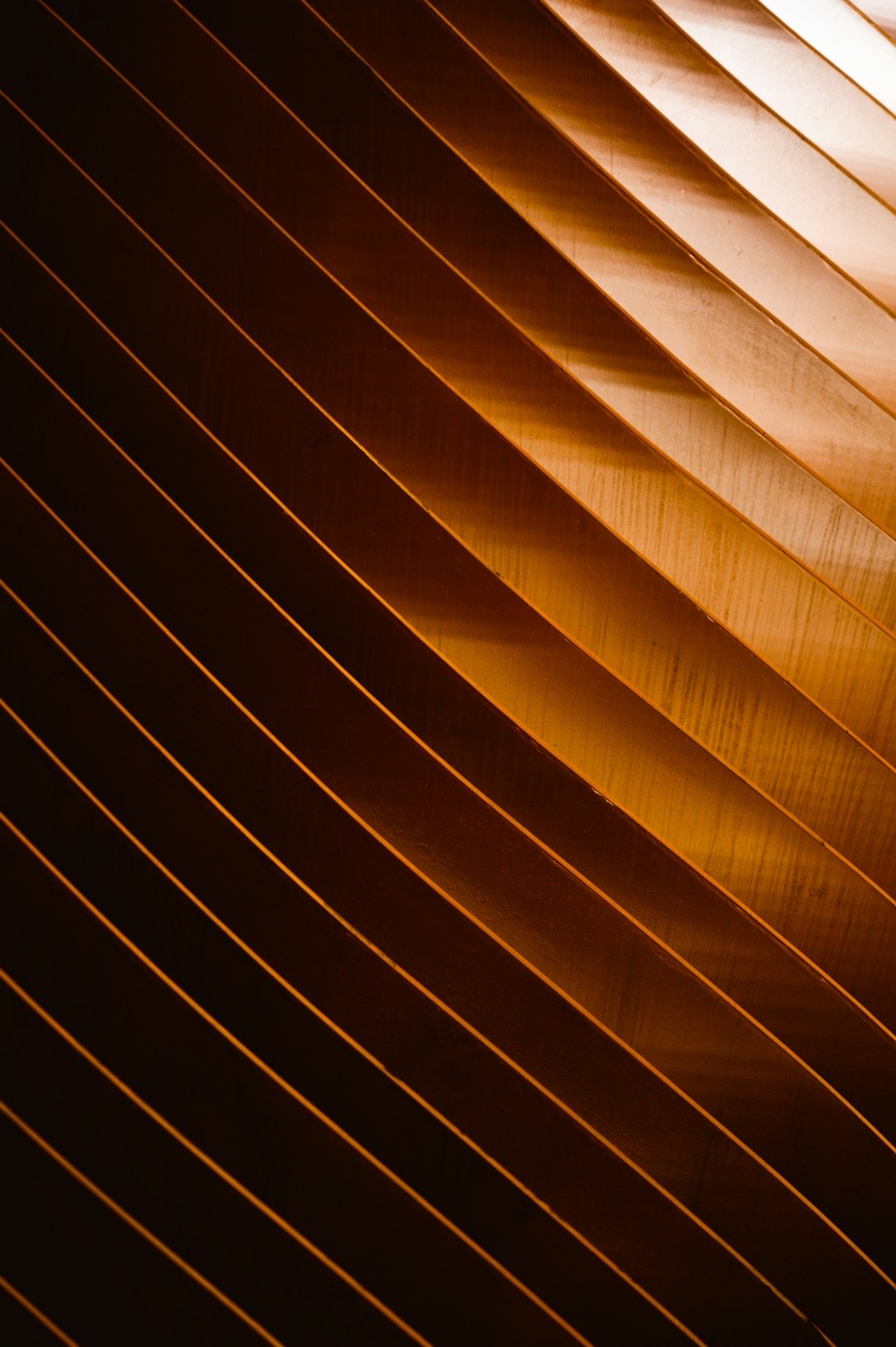 A closeup of the copper slats on an industrial ceiling, showing their unique texture and depth. The light from above casts long shadows across them, creating a dramatic play of highlights and lowlights that accentuates each wood grain. This shot was captured with a Canon EOS1D X Mark III using Kodak Gold 400 film to emphasize the rich tones and textures in the photograph in the style of film photography. –ar 85:128