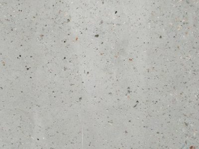 A flat surface of light grey concrete with small speckles, showcasing the texture and quality of the real cement. The background is neutral and uncluttered to highlight the roughness or graininess in the material's surface. This is suitable for use as an image for product packaging, showcasing the concrete features such as shine, luster, and natural materials in the style of natural materials. --ar 4:3