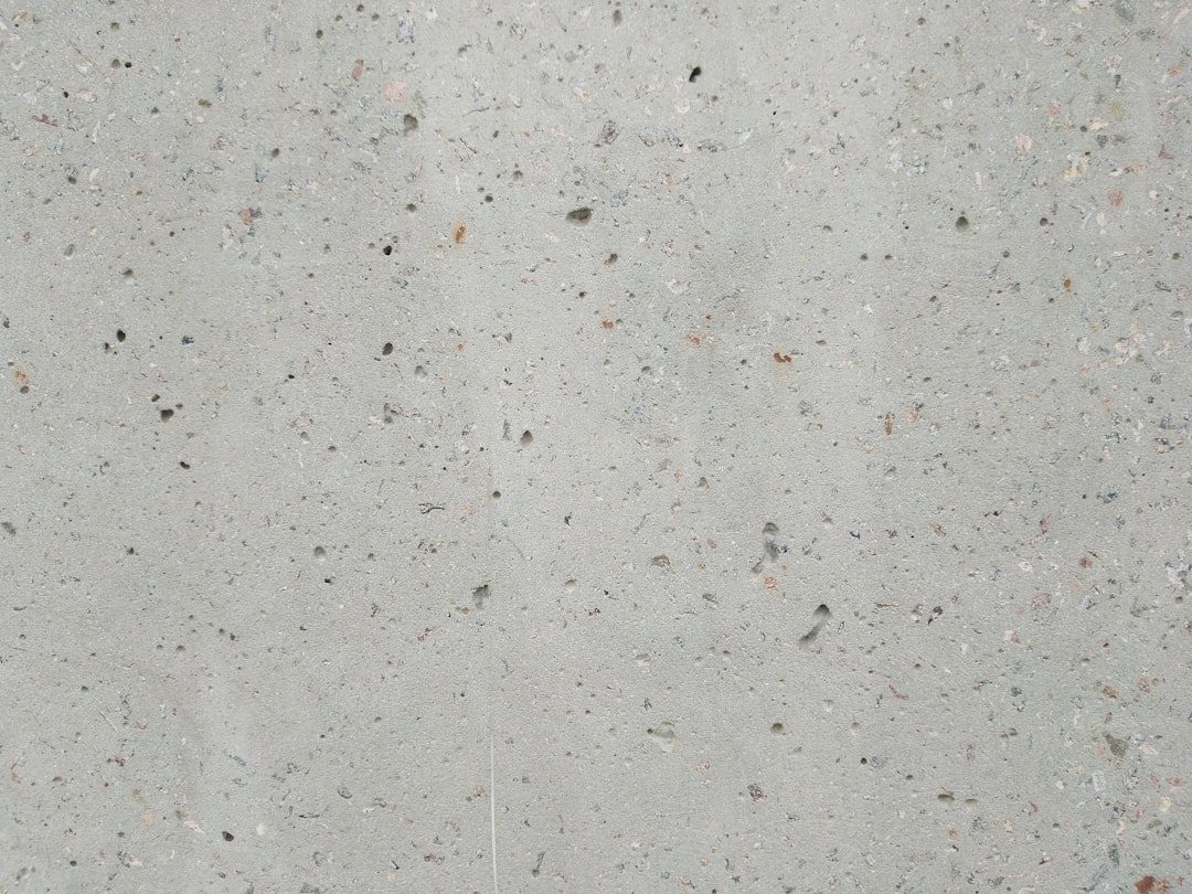 A flat surface of light grey concrete with small speckles, showcasing the texture and quality of the real cement. The background is neutral and uncluttered to highlight the roughness or graininess in the material’s surface. This is suitable for use as an image for product packaging, showcasing the concrete features such as shine, luster, and natural materials in the style of natural materials. –ar 4:3