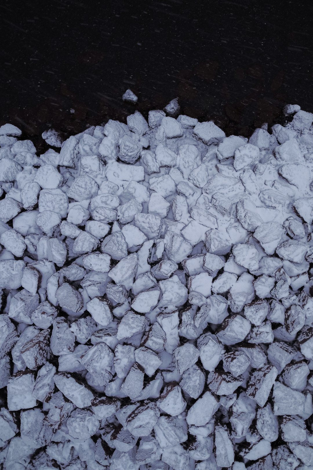 white rocks on the ground, top view, dark background, snowing –ar 85:128