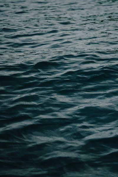 Dark blue water, flat sea surface, shot from the side, minimalist style, high definition photography, real life scenes, closeup shots, blurred focus, and no waves on the water's surface. The entire scene is dark gray with subtle color changes in shades of deep green and navy blue. A calm atmosphere envelops everything. This photo was taken in the style of Sony Alpha A7 III camera with an aperture setting of f/8, ISO 200, focal length of 56mm, and shutter speed of one using multiple exposure mode. --ar 85:128