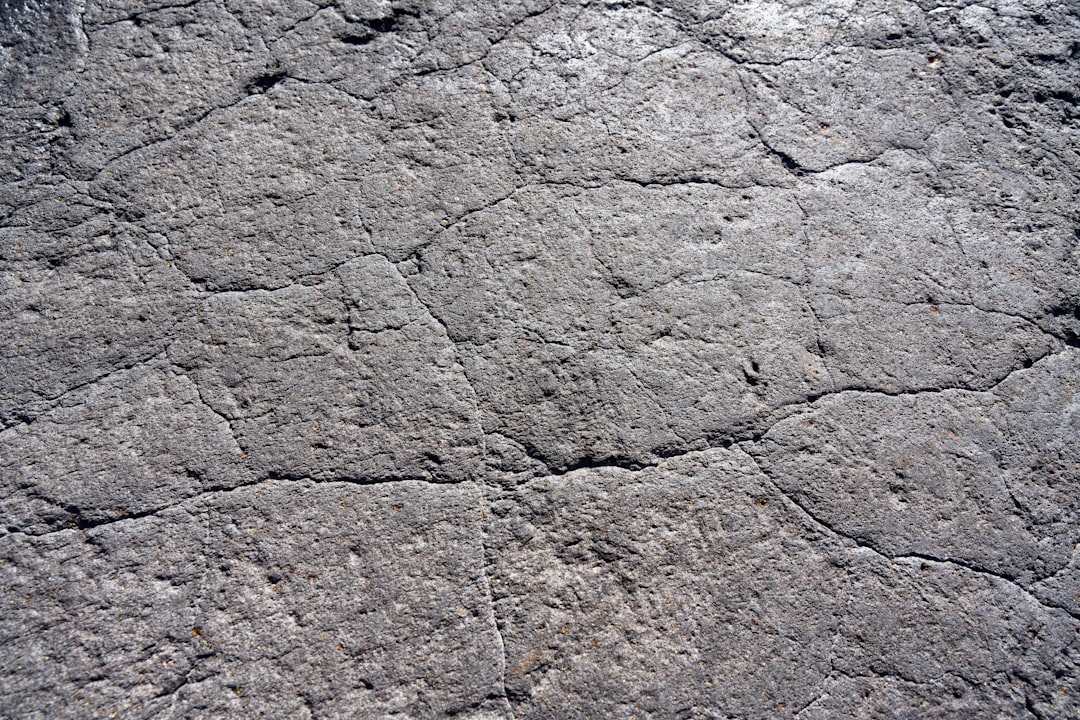 A flat concrete texture with small cracks, top view, close up, in the style of unknown artist. The texture has a worn look with minor fissures. It is a close perspective showing the details of the surface. –ar 128:85