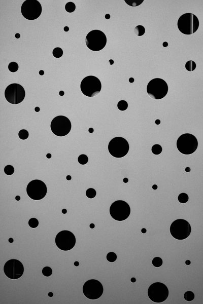 photograph of holes on white wall, monochrome, minimalism, black and grey, lots of circles --ar 85:128