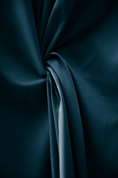 a dark teal silk fabric, with drapery and folds, against black background, high resolution, studio lighting, high quality photo, pro color grading, soft shadows, no contrast, clean sharp focus --ar 85:128