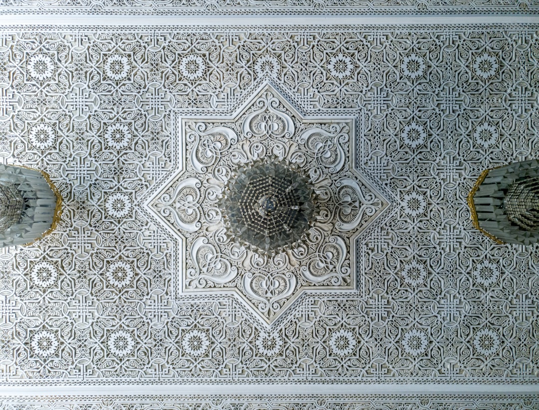 Moroccan ceiling with intricate white and grey patterns, ornate details, symmetrical designs, delicate lacework in the style of symmetrical designs. –ar 128:97