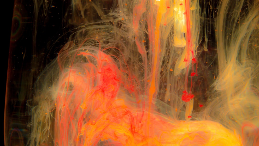 Closeup of an orange and yellow abstract painting in water on a black background, with fluid lines and shapes, light white and dark red, creating visual effects with water and paint, light gold and magenta, high resolution, photographed in the style of a Hasselblad H6D400c medium format film camera, with hyper realistic details. –ar 16:9