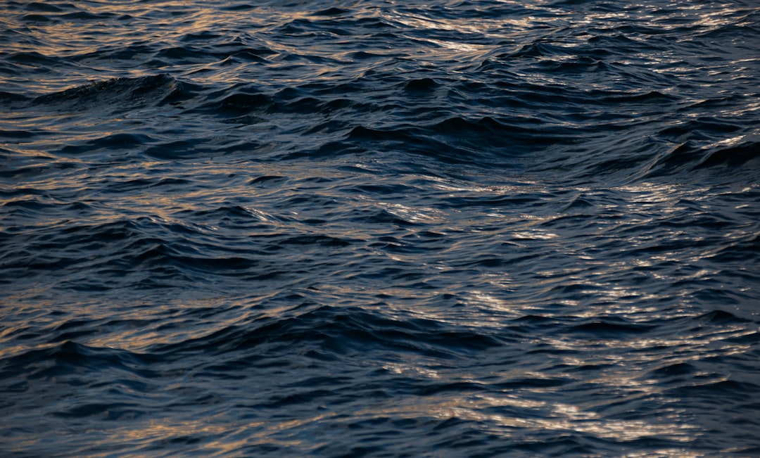 photograph of the dark blue sea with gentle ripples at sunset, texture, natural light, high resolution –ar 128:77