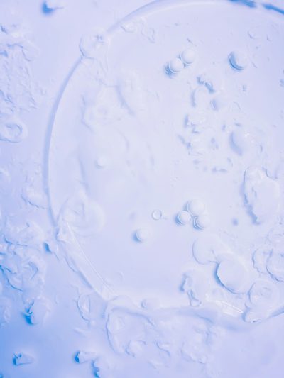 White background, top view of circular water drops on the surface of blue milk liquid, in the style of high definition photography, macro photography, bright and light colors, delicate texture, clear details, water droplets --ar 3:4