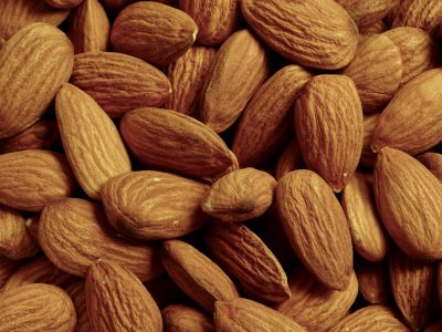 Al subscribed to the natural color scheme of an almond background. The image showcases an up close view of a pile of raw, unbaked and dry whole organic almonds, arranged in neat rows with no logos or labels on them. This photo highlights their texture and shape in the style of Al. --ar 4:3