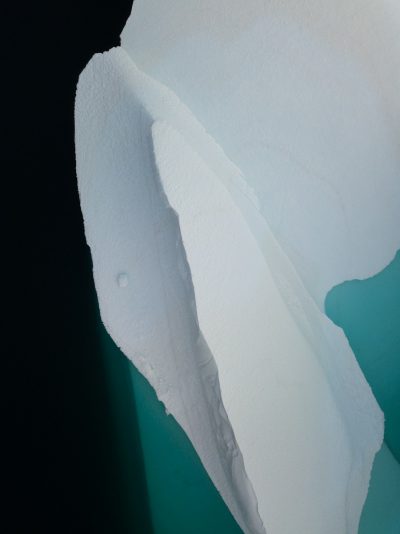 A close-up photograph of an iceberg in the style of James Arrondel, with a minimalist and aerial view style, featuring green and blue tones and white snow, composed of simple shapes with high contrast and high resolution. --ar 95:128