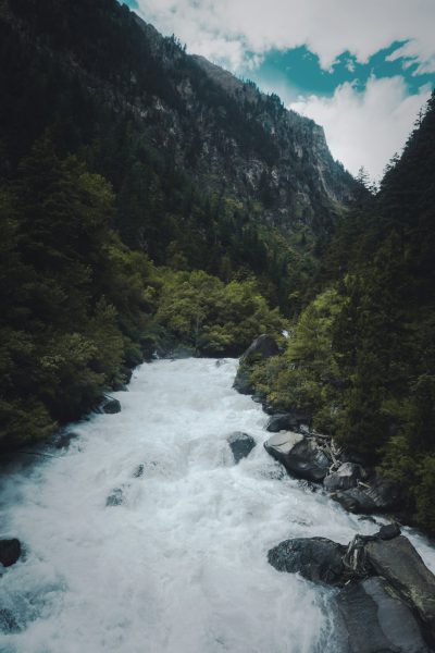 photo of white river in the mountains, green forest on both sides, white water rapids, high angle shot, wide lens, unsplash photography style, in the style of unsplash --ar 85:128