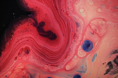 close up of red and pink paint swirls with blue bubbles, black background, --ar 128:85