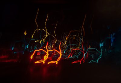 Abstract light painting photography of the night sky with blurry neon lights, black background, yellow and red lines, dark blue glowy outline shapes of dancing figures --ar 128:87