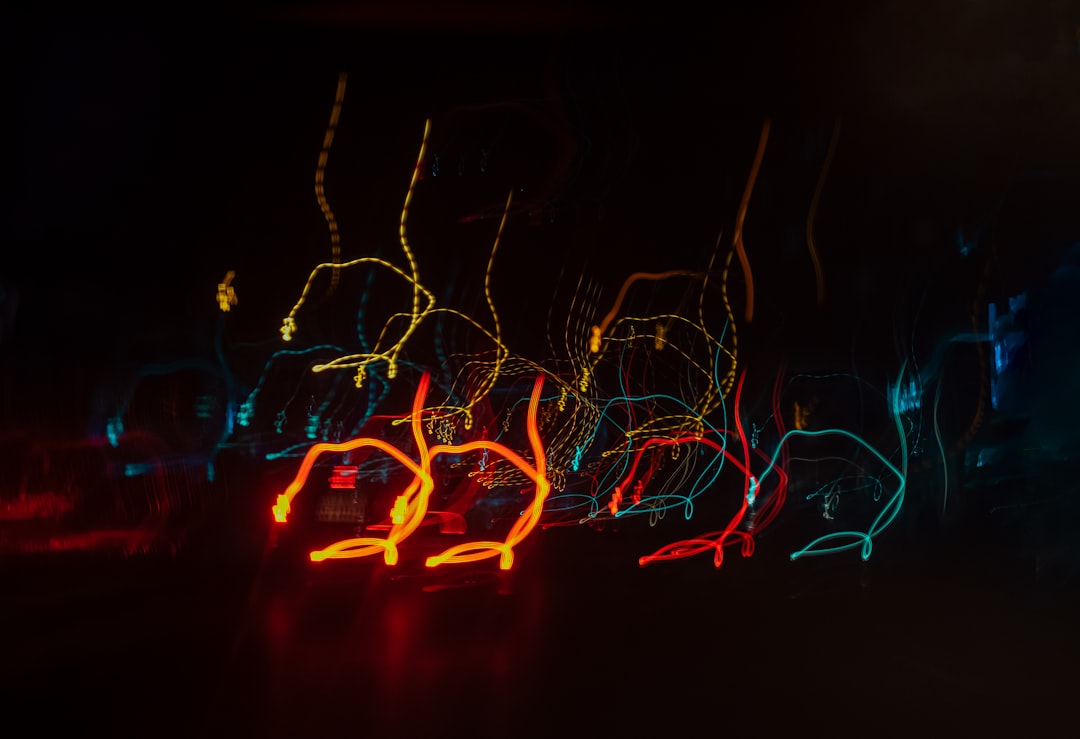 Abstract light painting photography of the night sky with blurry neon lights, black background, yellow and red lines, dark blue glowy outline shapes of dancing figures –ar 128:87