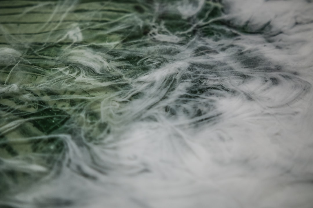 A closeup of green and white thick spider silk, swirling in the air with soft light. The background is blurred and indistinct due to its focus on capturing details. It creates an atmosphere that feels like being surrounded by misty clouds or flowing water, adding depth and texture to the scene. This is suitable for creative projects where detail is objects like fabrics, , fur etc . can be used. –ar 128:85