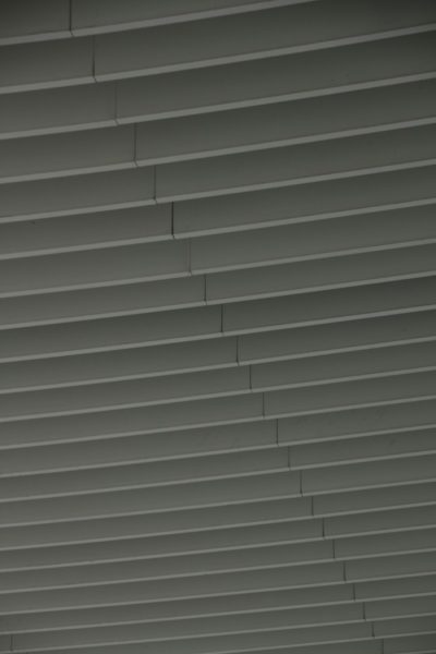 Closeup of grey horizontal slats on the ceiling, creating an abstract pattern. The background is dark gray and the texture adds depth to the composition. --ar 85:128